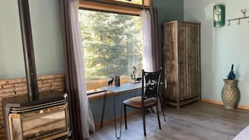 A cozy room with a fireplace, a window with curtains, a wooden cabinet, and a chair.