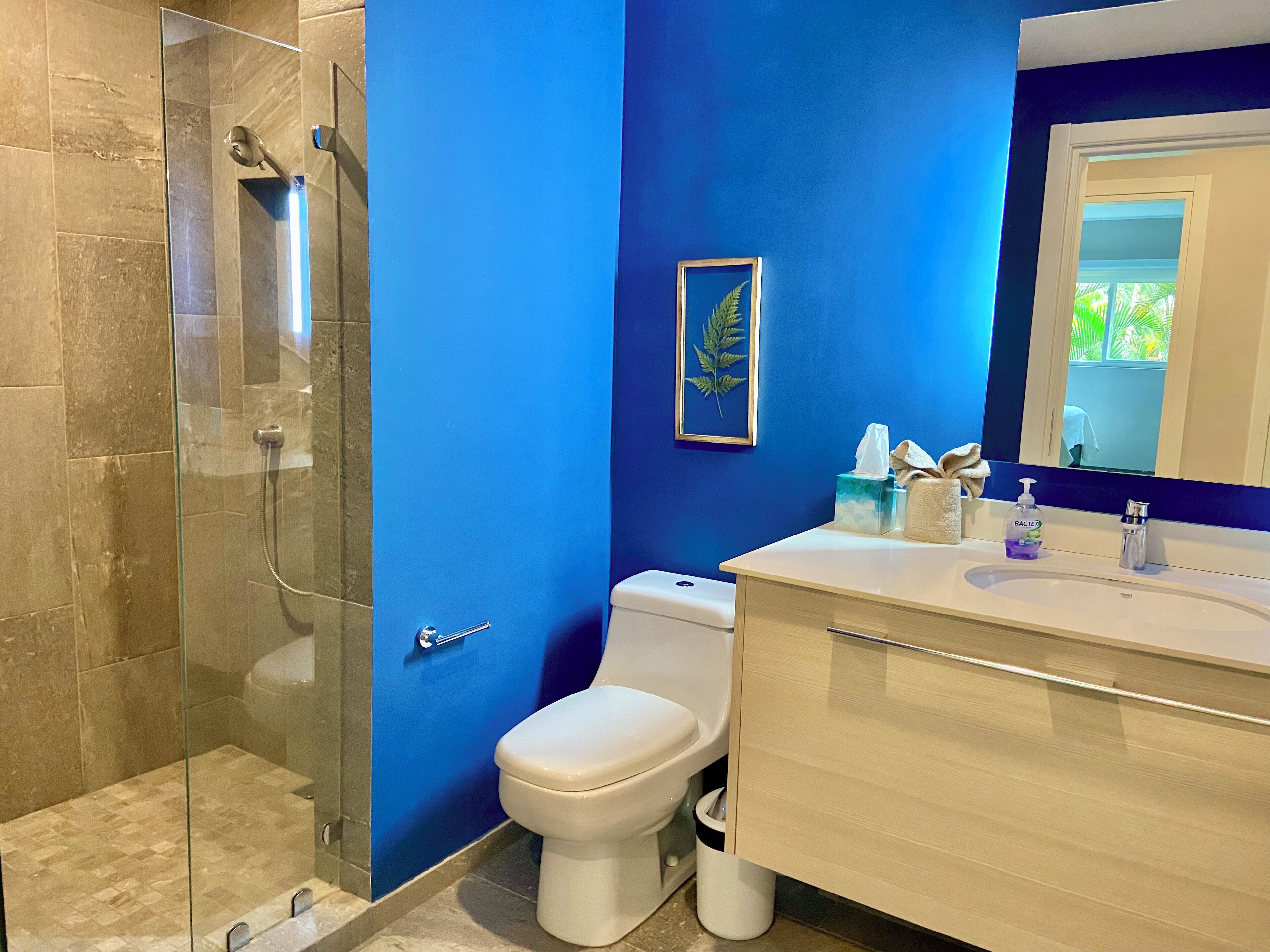 Een badkamer met een douchecabine van glas, een wit toilet en een wastafel met spiegel.
