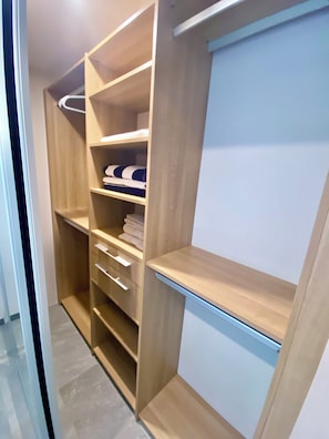 Un dressing avec de nombreuses étagères et tiroirs, doté d’une finition en bois clair et d’un intérieur blanc.