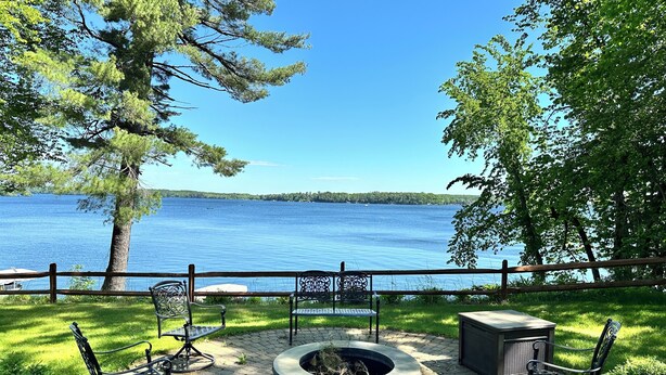 Eine Terrasse mit Sitzgelegenheiten im Freien, einem Feuerkorb und Blick auf einen See.