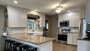 Eine moderne Küche mit weißen Schränken, Granit Arbeitsplatten, einem Edelstahlkühlschrank und einem Einbauofen.