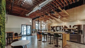 A modern kitchen with stainless steel appliances, a bar area with stools, and a seating area with a round table and chairs. - The Exchange. Big Luxury Loft, XCHNG. Modern Loft in the heart of Effingham.  (Effingham)