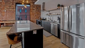 A modern kitchen with a large island, stainless steel appliances, and exposed brick walls. - The Exchange. Big Luxury Loft, XCHNG. Modern Loft in the heart of Effingham.  (Effingham)