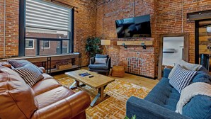 Ein gemütliches Wohnzimmer mit Ledersofas, einem Holztisch und einer Ziegelwand.