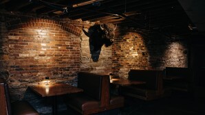 A restaurant interior with brick walls, wooden tables, and benches. - XCHNG 4 Apartments Downtown. Side by Side. (Effingham)