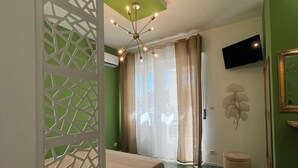 Un dormitorio con cama, televisor, un adorno en la pared y pared verde.