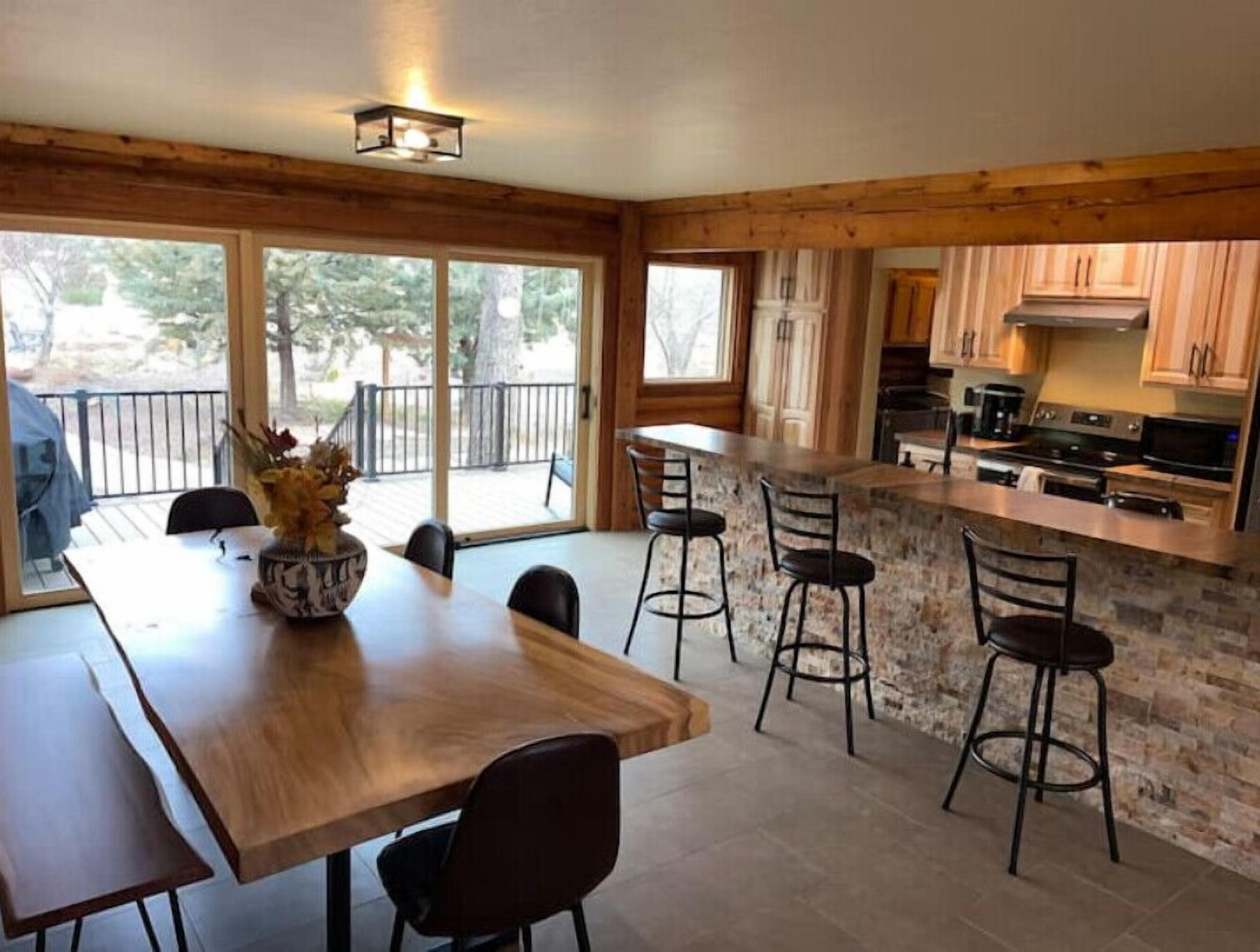 A modern kitchen with a stone island, wooden cabinets, and a dining area with a large table and chairs.