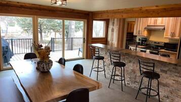 A modern kitchen with a stone island, wooden cabinets, and a dining area with a large table and chairs.