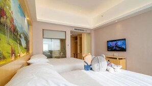 Hotellihuone, jossa on suuri sänky, televisio, taulu ja vaatekaappi.