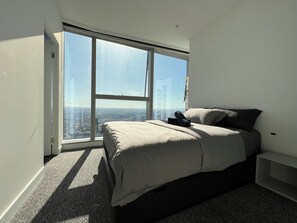 Panoramic city views from a large window, paired with a comfortable bed and minimalist design.
