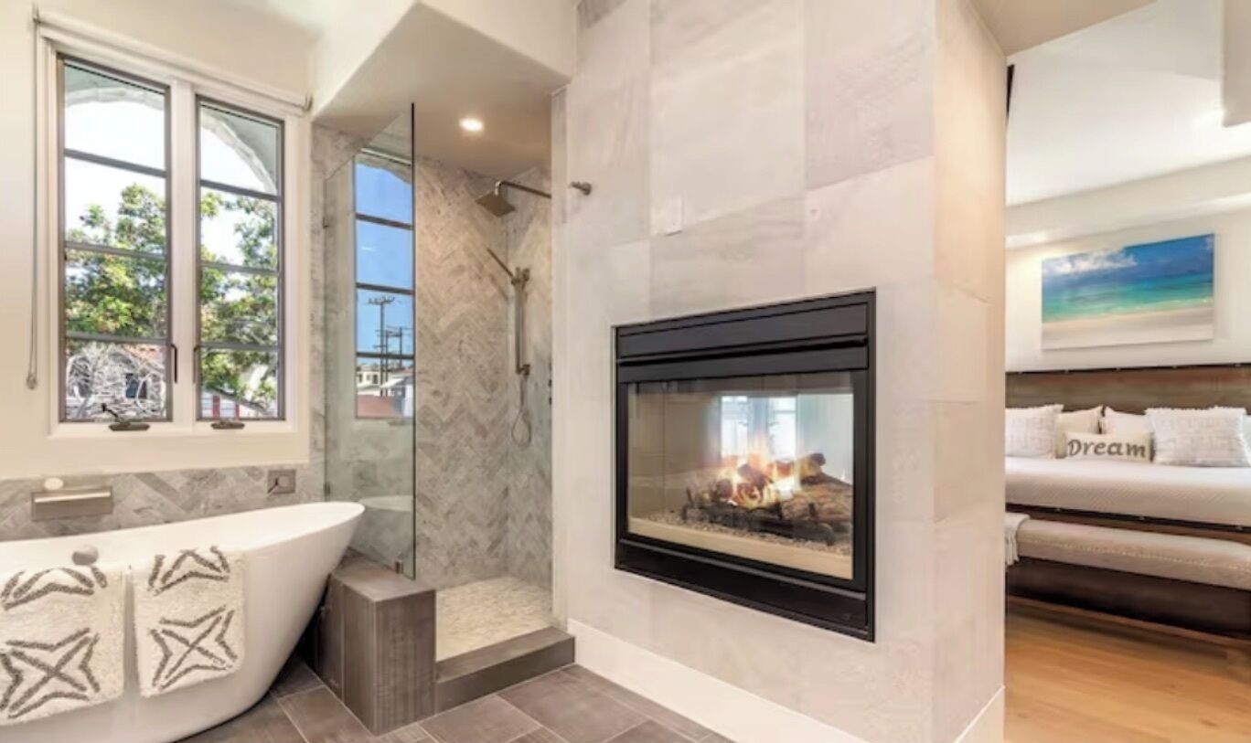 Een moderne badkamer met een vrijstaand bad, een douche en een open haard.