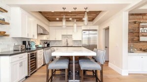 Une cuisine moderne dotée d’un îlot central, de luminaires suspendus et d’un plafond en bois.