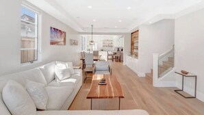 Un salon spacieux avec un canapé blanc, une table basse en bois et un escalier menant à l’étage supérieur.