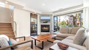 Un salon moderne avec une table basse en bois, un canapé beige et une cheminée.