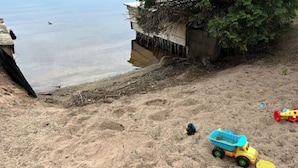 Une zone de plage sablonneuse avec un camion à benne basculante jouet et d’autres jouets.