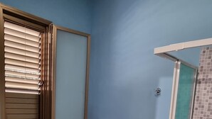 Een badkamer met een houten plafond, een blauwe wand, een toilet, een bidet, een wastafel en een douchecabine.