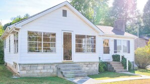 A single-story white house with a stone foundation, large windows, and a front porch.