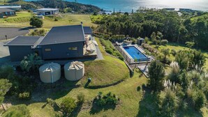 An aerial view of a property with a large house, a swimming pool, and a view of the sea.