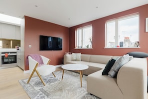 A modern living room with a sofa, a coffee table, and a television mounted on the wall.