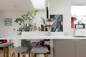 A modern kitchen with a white countertop, a decorative trophy, and a bookshelf. - Spacious and Stylishly Designed 2BD Flat, Clapham (London)