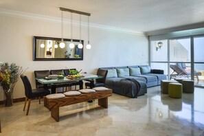 A modern living room with a glass dining table, a sofa, and a bench.