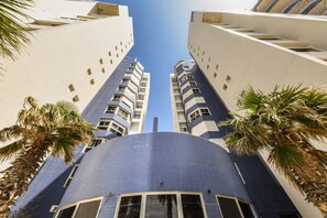 Un grattacielo con una cupola blu caratteristica e facciate bianche, circondato da palme.