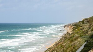 Un paysage côtier avec une plage, des falaises rocheuses et un ciel dégagé.