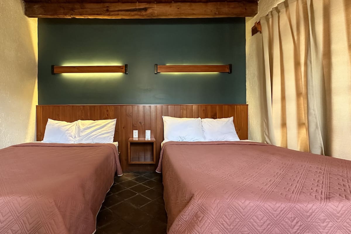 Une chambre avec deux lits, des têtes de lit en bois et un mur vert.