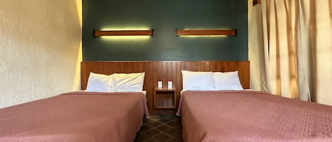 A room with two beds, wooden headboards, and a green wall.