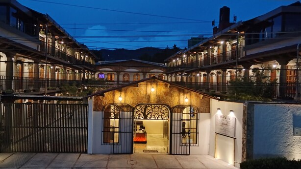 Fachada de hotel de piedra, con varios balcones y una entrada protegida por una reja.
