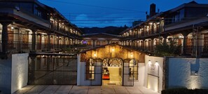 Fachada de hotel de piedra, con varios balcones y una entrada protegida por una reja.