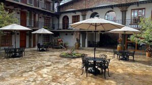Un patio con suelo de piedra, mesas exteriores y sombrillas.