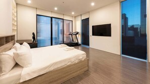 A modern bedroom with a bed, exercise equipment, and a city view. - Spacious CBD Penthouse w Parking Pool and Gym (West Melbourne)