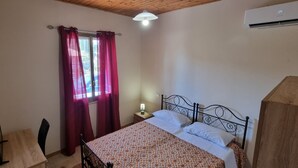 A bedroom with a bed, a nightstand, a table, and a chair. - Room in cottage Holiday home in Palmi. (Palmi)
