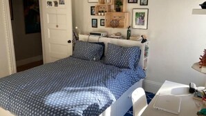 Ein Schlafzimmer mit einem Bett, einem Schreibtisch mit einem Laptop und einer Tür.
