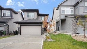 Un quartier résidentiel avec des maisons modernes, une allée et un petit arbre.