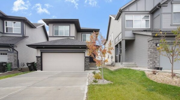 Un quartier résidentiel avec des maisons modernes, une allée et un petit arbre.