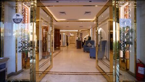 A hotel lobby with a marble floor, a reception desk, and a blue sofa. - PRIMOTEL Elite As Salamah (Jeddah)
