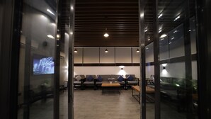An interior space with a seating area, a wooden table, and a television screen. - PRIMOTEL Elite As Salamah (Jeddah)