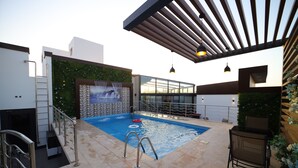A rooftop pool with a glass enclosure, a ladder, and a grill area. - PRIMOTEL Elite As Salamah (Jeddah)
