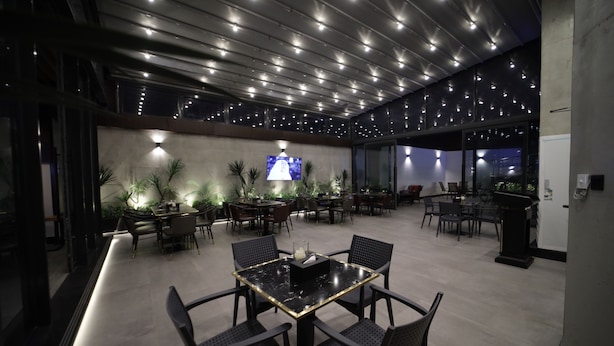 A modern dining area with a central table, multiple chairs, and ambient lighting. - PRIMOTEL Elite As Salamah (Jeddah)