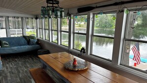 Une pièce chaleureuse avec un banc en bois, un canapé bleu et de grandes fenêtres donnant sur un lac.