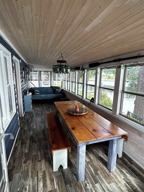 A cozy room with a wooden bench, a table, and a view of the outdoors. - A cozy Adirondack cabin with mountain and lake views! (Wells)