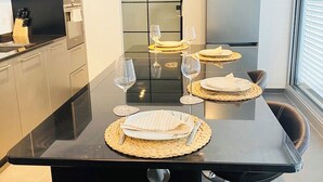 A modern kitchen with a black countertop, stainless steel appliances, and a dining area with a black table, four chairs, and a large window.