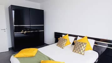 A modern bedroom with a large bed, a black wardrobe, and a white ceiling.