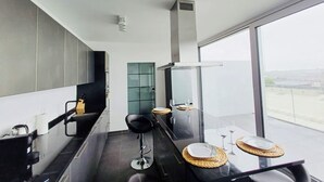 A modern kitchen with a dining area, large windows, and a view of the city.