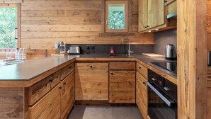 A modern kitchen with wooden cabinetry, a built-in oven, and a window above the sink. - Fauvettes 4 a warm cocoon in Meribel Village (Les Allues)