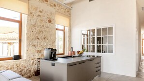 Una cocina moderna con una pared de piedra, una cafetera y un frutero en la encimera.