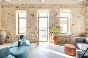 Une pièce spacieuse avec un mur en pierre, une grande fenêtre et une vue sur la mer.