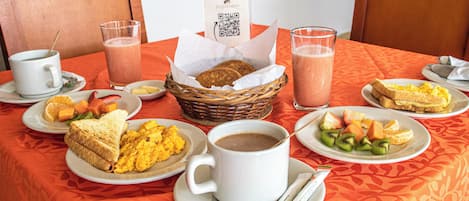 Una escena de desayuno con distintos platos, una taza de café y un cartel con un código QR en la mesa.